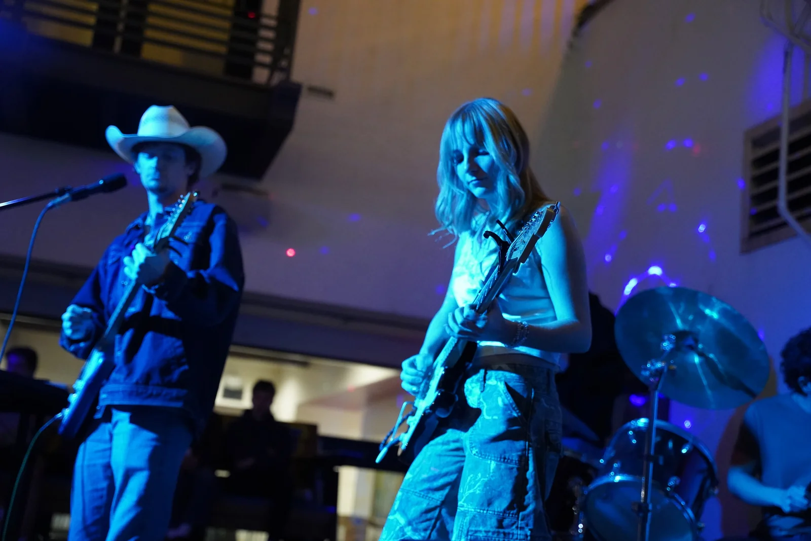 Two South of Sober guitarists playing side by side under blue stage lights
