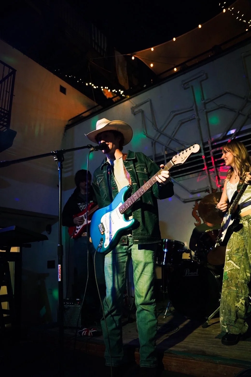 Miles singing with his blue guitar and cowboy hat beside the band